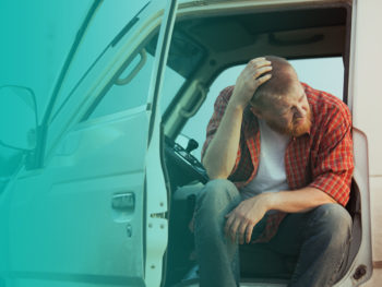 A man in a flannel shirt sitting in his truck with the door open