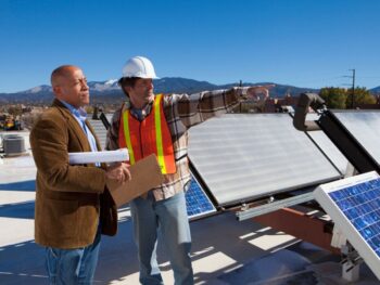 two men working on a roof near solar panels
