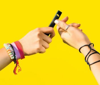 Students passing a JUUL vaping device. Learn more about vaping and the risks.