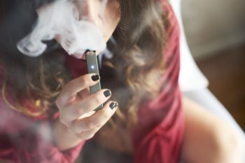 A teenage girl holds a JUUL vaping device. Learn more about vaping and how it impacts youth.