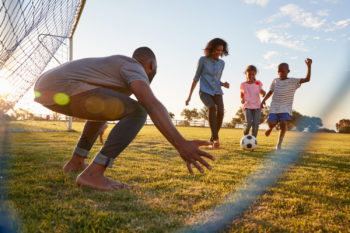 Family playing soccer in the park